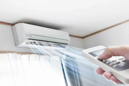 a hand holding a remote control intending to turn off the air conditioner